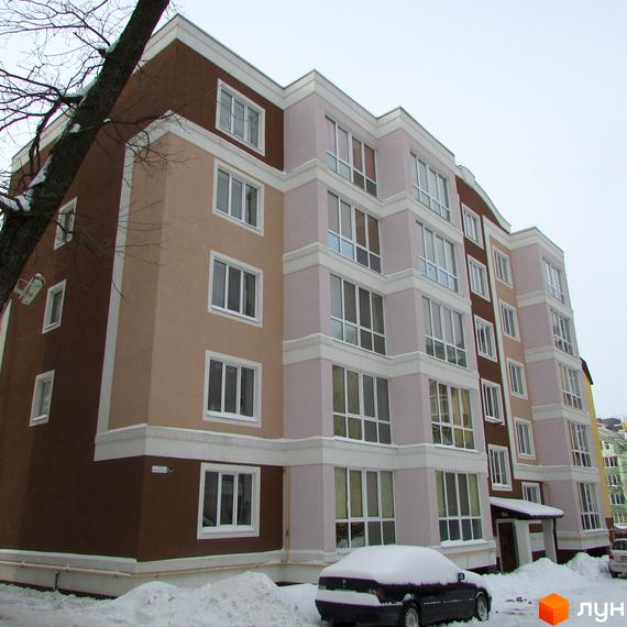 Житловий комплекс Фортуна: багатоповерховий будинок з фасадами у відтінках коричневого, бежевого та світло-рожевого, з білими віконними рамами. Прибудинкова територія вкрита снігом.