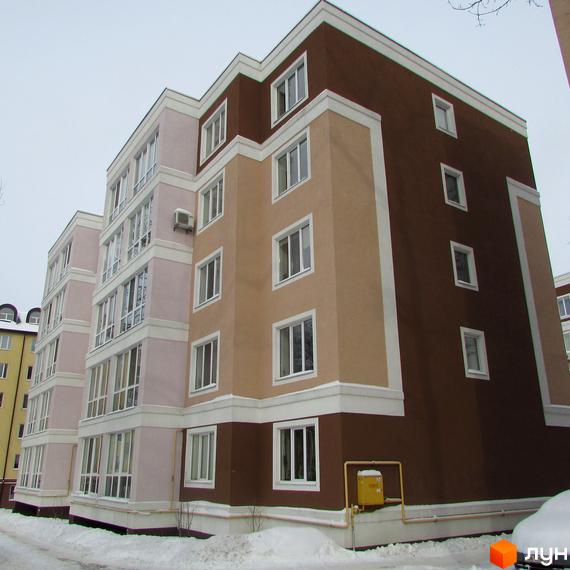 Новобудова Фортуна: багатоповерховий будинок з фасадами світло-коричневого, рожевого та темно-коричневого кольорів, прибудинкова територія вкрита снігом.
