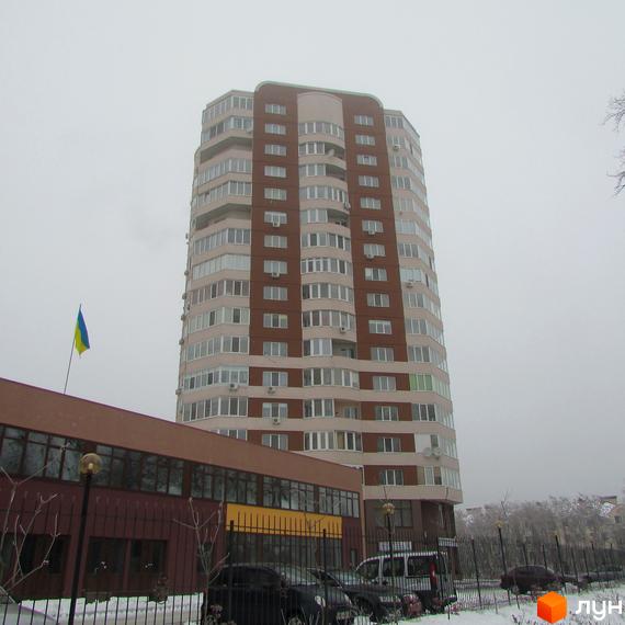 Житловий комплекс Шоколад: високий будинок з коричнево-світлим фасадом та багатьма вікнами. Перед ним розташована нижча будівля та засніжена територія.