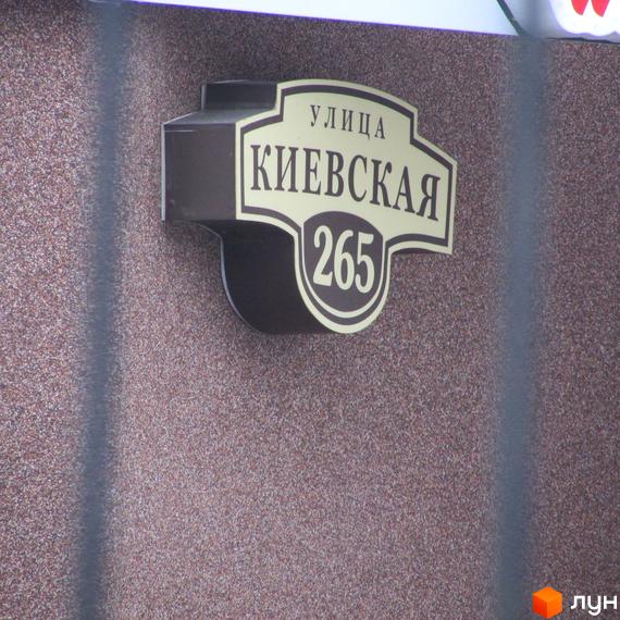 Вулична табличка з номером будинку 265 та назвою вулиці Київська, розташована на стіні житлового комплексу Шоколад.