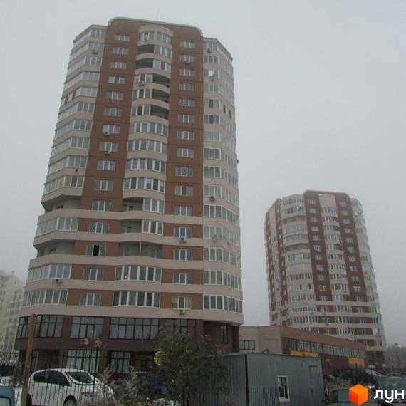 Житловий комплекс Шоколад: багатоповерхові будинки з коричнево-бежевим фасадом та численними вікнами. На передньому плані видно прибудинкову територію з парковкою.