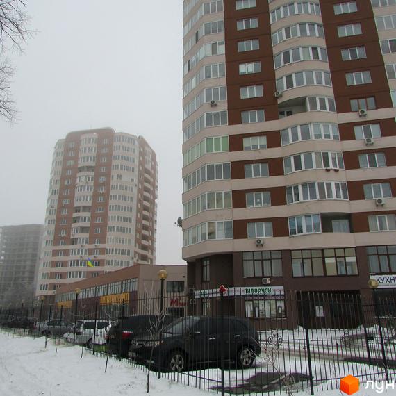 Житловий комплекс Шоколад: будинки з коричнево-бежевими фасадами. Засніжена прибудинкова територія з автомобілями та комерційними приміщеннями.