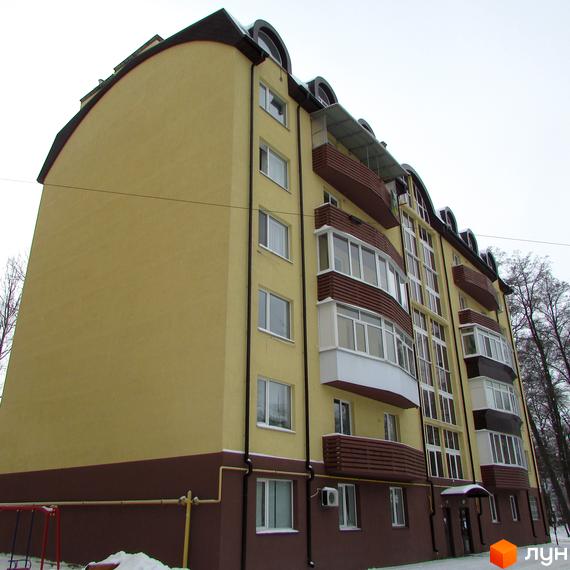 Житловий комплекс НовоОскольский: світло-жовтий багатоповерховий будинок з коричневим цоколем, балконами, великими вікнами та засніженою прибудинковою територією.