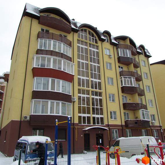 Багатоповерховий будинок Житлового комплексу НовоОскольский з жовтим фасадом, коричневою основою та великими вікнами. Навколо засніжена територія з дитячим майданчиком.