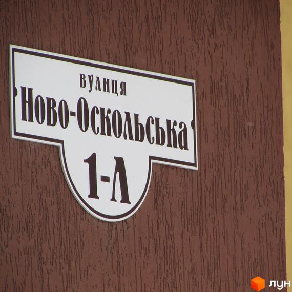 Табличка з адресою вулиця Ново-Оскольська, 1-А на коричневій стіні, що вказує на розташування Житлового комплексу НовоОскольский.