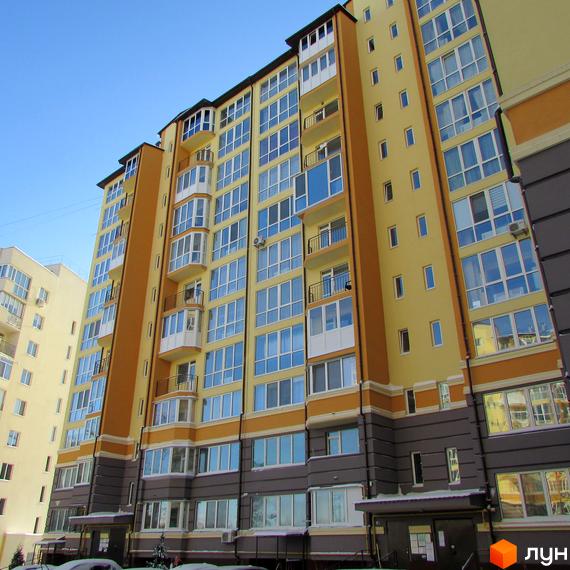 Житловий комплекс Французький квартал: багатоповерховий будинок жовто-оранжевого кольору з великими вікнами та балконами. Прибудинкова територія засніжена.