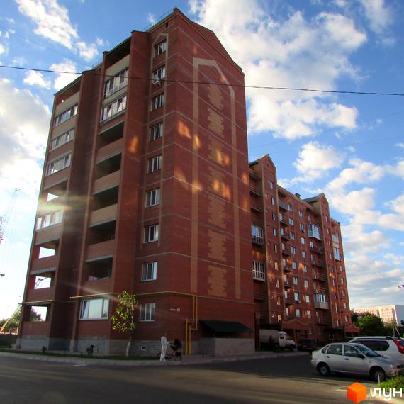 Житловий комплекс Левада - цегляна багатоповерхова новобудова з балконами та великими вікнами. На прибудинковій території видно автомобілі та пішоходів.
