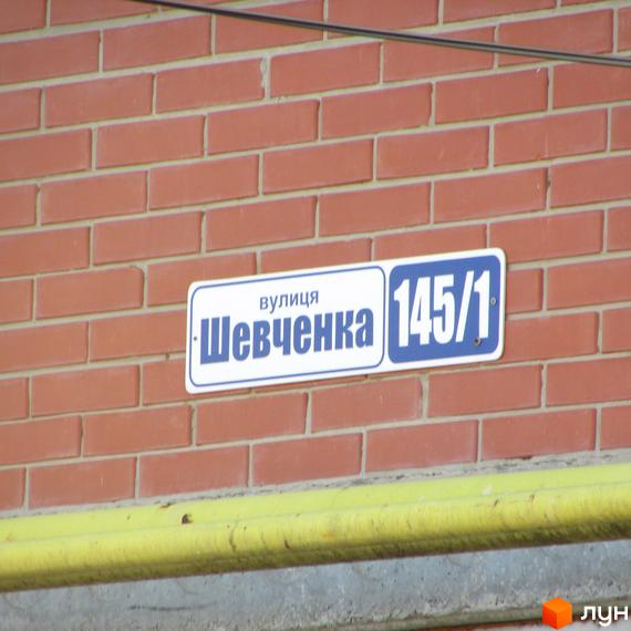 Адресна табличка на цегляній стіні будинку ЖК Левада. На табличці вказана вулиця Шевченка, 145/1.