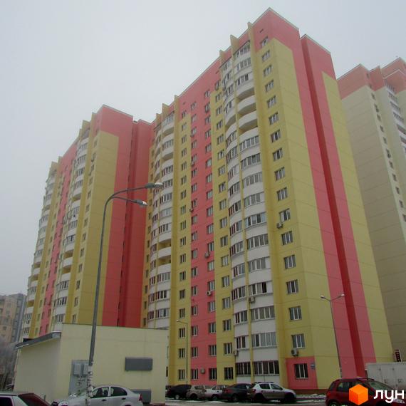 Житловий комплекс на вул. Симона Петлюри (Черняховського), 36, 36а, 36б. Багатоповерховий будинок з яскравим фасадом у жовто-рожевих тонах. Перед будинком розташована прибудинкова територія з автомобілями та ліхтарями.