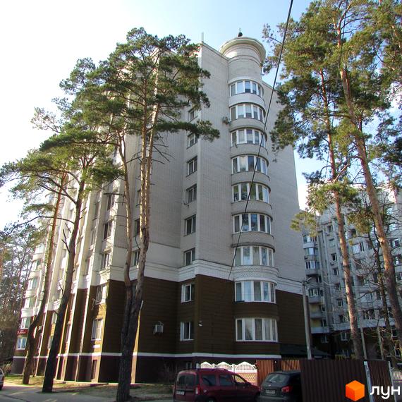 Зовнішній вигляд будинку ЖК Тургенівська з вікнами та балконами, оточений деревами. На прибудинковій території видно автомобілі та паркан.