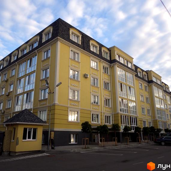 Житловий комплекс Софіївський Пасаж з жовтим фасадом та темним дахом. Навколо новобудови розташована прибудинкова територія з парковкою та деревами.