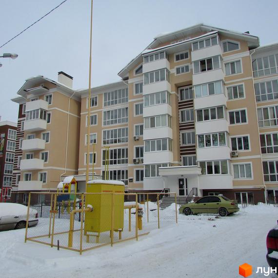 Зовнішній вигляд житлового комплексу на вул. Мечникова, 103, з фасадом бежевого кольору та численними балконами. Прибудинкова територія вкрита снігом, видно дитячий майданчик та автомобіль.