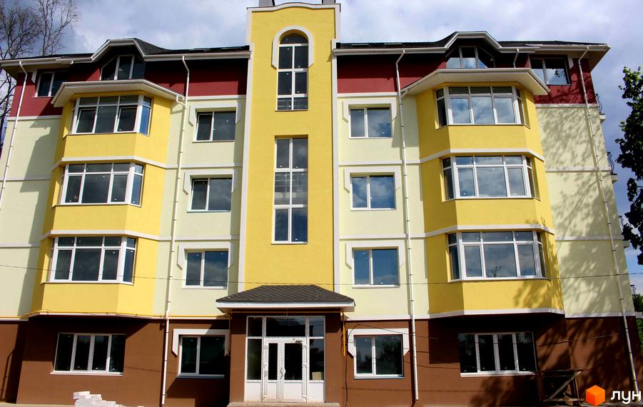 Фасад багатоповерхового будинку ЖК Ваша квартира з жовтими та коричневими елементами. На фасаді великі вікна, що забезпечують гарне освітлення. Вхідна група з козирком.