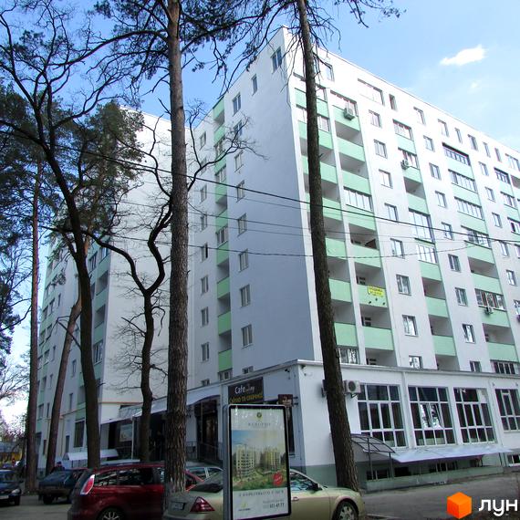 Зовнішній вигляд новобудови ЖК Сосновий двір з балконами та вікнами. Навколо будинку ростуть дерева, а біля нього розташовані автомобілі.