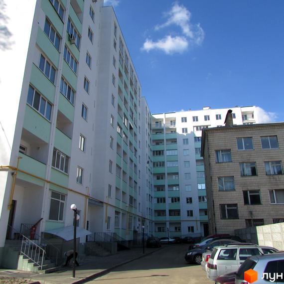 Зовнішній вигляд новобудови ЖК Сосновий двір з світлими фасадами та зеленими елементами. Прибудинкова територія з парковкою та зеленими насадженнями.