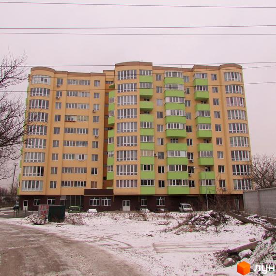 Зовнішній вигляд багатоповерхового будинку ЖК Зірка Дніпра з жовто-зеленими фасадами та великою кількістю вікон. Навколо будинку видно засніжену територію та дерева.