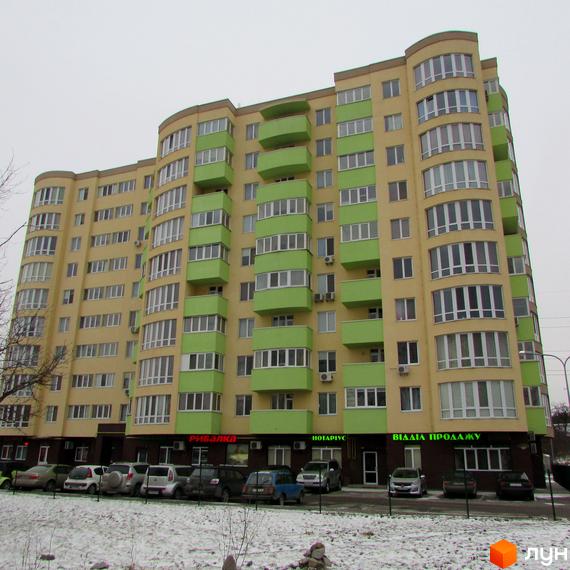 Житловий комплекс Зірка Дніпра. Багатоповерховий будинок жовто-зеленого кольору з виступаючими балконами. Перед будинком розташована парковка та засніжена територія.