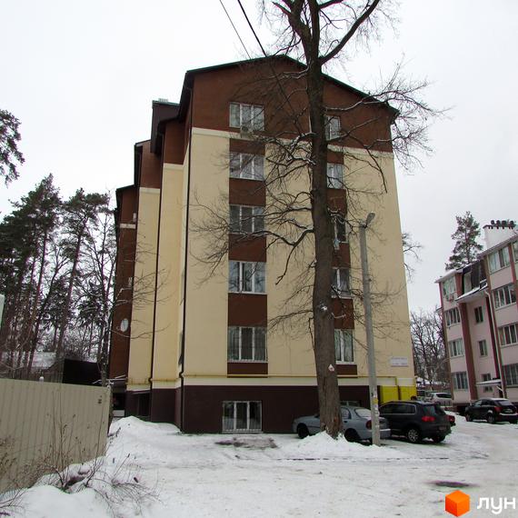 Зовнішній вигляд будинку на вул. Лермонтова, 6е, у зимовий період. Прибудинкова територія засніжена, видно дерева та припарковані автомобілі.