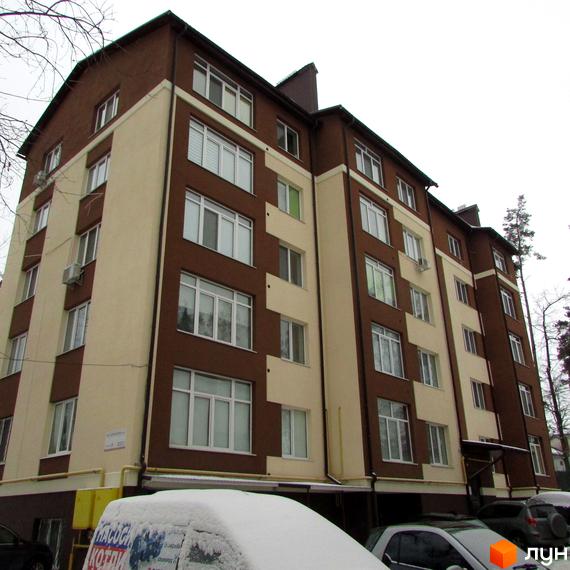 Зовнішній вигляд новобудови на вул. Лермонтова, 6е, з коричнево-бежевим фасадом та численними вікнами. На прибудинковій території видно засніжені автомобілі.