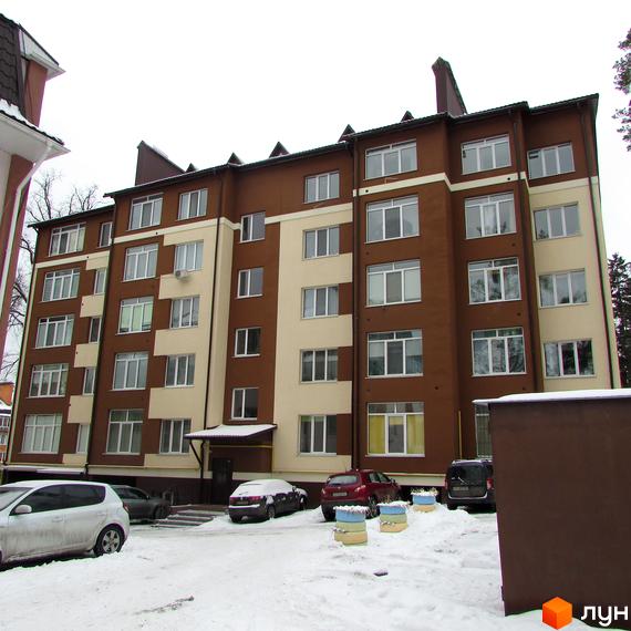 Новобудова на вул. Лермонтова, 6е. П'ятиповерховий будинок коричнево-бежевого кольору з великою кількістю вікон. Біля будинку розташовані припарковані автомобілі та засніжена територія.