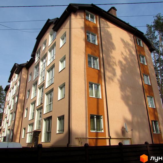 Житловий комплекс Сосновий бір - багатоповерховий будинок з бежевим та помаранчевим фасадом, вікнами та балконами. Поруч дерева та паркан.