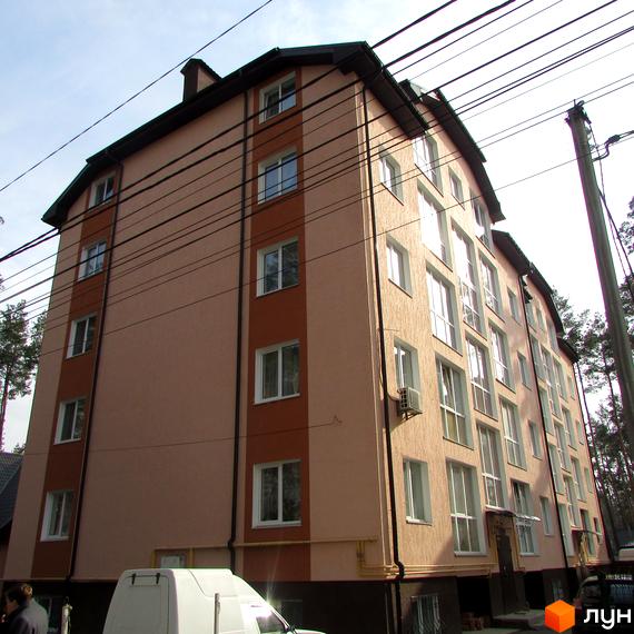 Житловий комплекс Сосновий бір. Багатоповерховий будинок з світло-рожевим фасадом та коричневими вставками, великими вікнами. Навколо будинку дерева.
