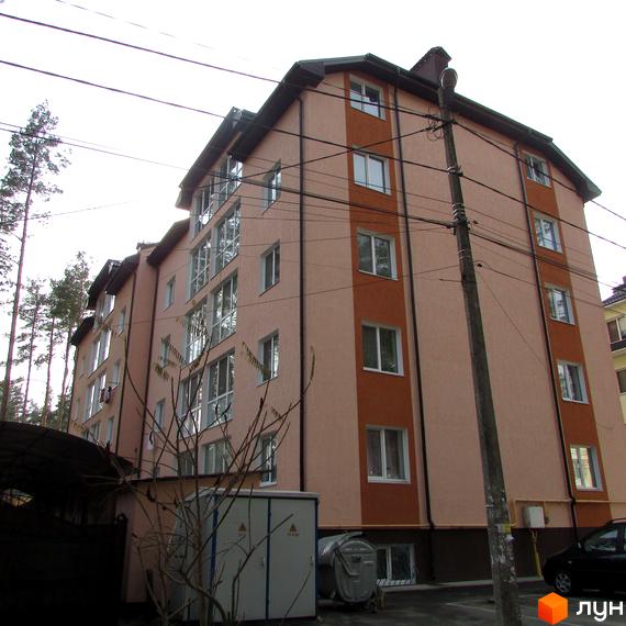 Зовнішній вигляд будинку ЖК Сосновий бір з вікнами та балконами. На прибудинковій території видно електрощитову та дерева.