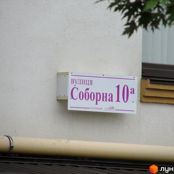 Вулична табличка ЖК Щасливий на Петропавлівській вулиці, Соборна 10а. Зовнішній вигляд фасаду будівлі.