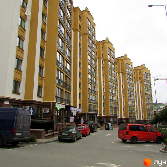 Житловий комплекс Щасливий на Петропавлівці – це сучасна новобудова з жовто-білим фасадом та численними вікнами. Перед будинком розташований паркінг та проїжджа частина.