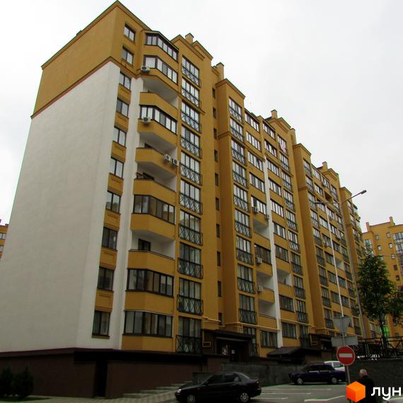 Житловий комплекс Щасливий на Петропавлівці: жовтий багатоповерховий будинок з білою стіною та балконами. Прибудинкова територія з дорогою та припаркованими авто.