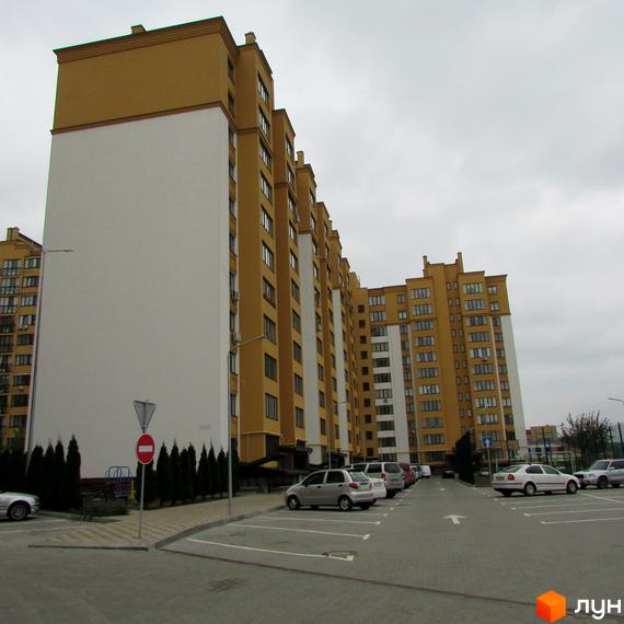 Житловий комплекс Щасливий на Петропавлівці. Багатоповерхові будинки жовто-білого кольору з паркінгом та зеленими насадженнями.