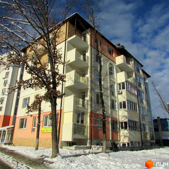 Зовнішній вигляд житлового комплексу Квітневий у зимовий період. Багатоквартирний будинок з балконами та вікнами, оточений деревами та засніженою територією.