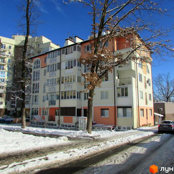 Зовнішній вигляд багатоповерхового будинку ЖК Квітневий у зимовий період. Навколо будинку засніжена територія та дерева.