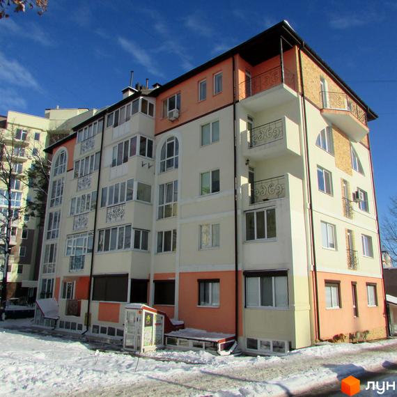 Зовнішній вигляд будинку ЖК Квітневий у зимовий період. Багатоповерхівка з балконами та вікнами, на тлі блакитного неба та снігу.