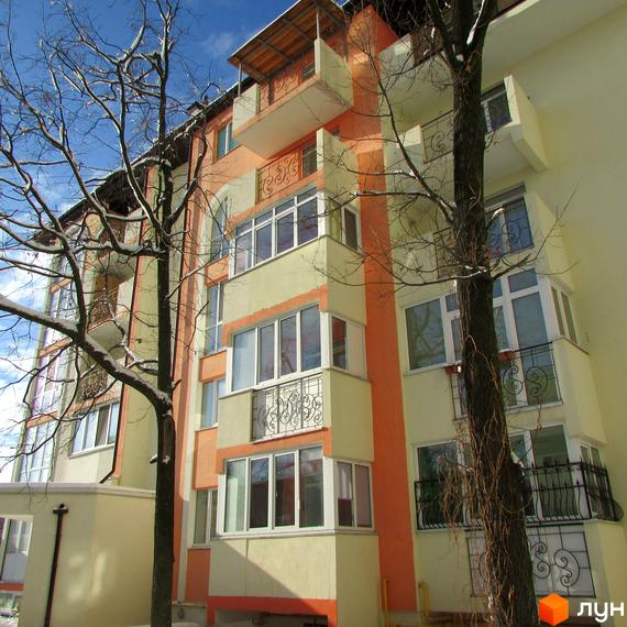 Зовнішній вигляд житлового комплексу Квітневий у зимовий період. Будинок з балконами та вікнами, оточений деревами.