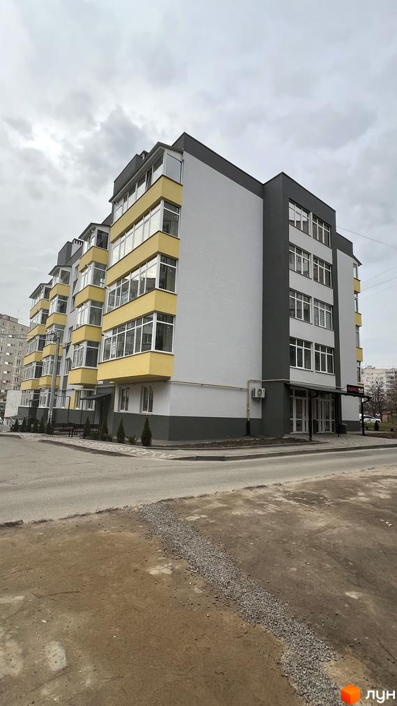 Зображення фасаду будинку на вулиці Польова, 8. Багатоповерхова будівля з великими вікнами та балконами, розташована на перехресті вулиць.