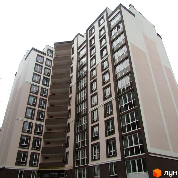 Зовнішній вигляд новобудови ЖК Парковий з великою кількістю вікон та балконів. Будинок має світлий фасад з коричневими елементами.