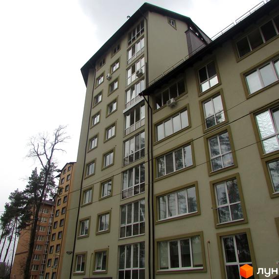 Житловий комплекс Парковий – висотна будівля зі світлим фасадом та численними вікнами. Поруч видно дерева та іншу будівлю.