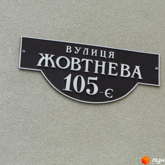 Вулична табличка з назвою вулиці Жовтнева, 105-є. Зовнішній вигляд будівлі житлового комплексу Парковий.