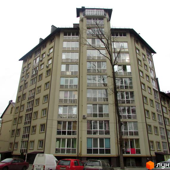 Зовнішній вигляд багатоповерхового житлового комплексу Парковий з численними вікнами та балконами. Перед будинком розташовані автомобілі та дерева.