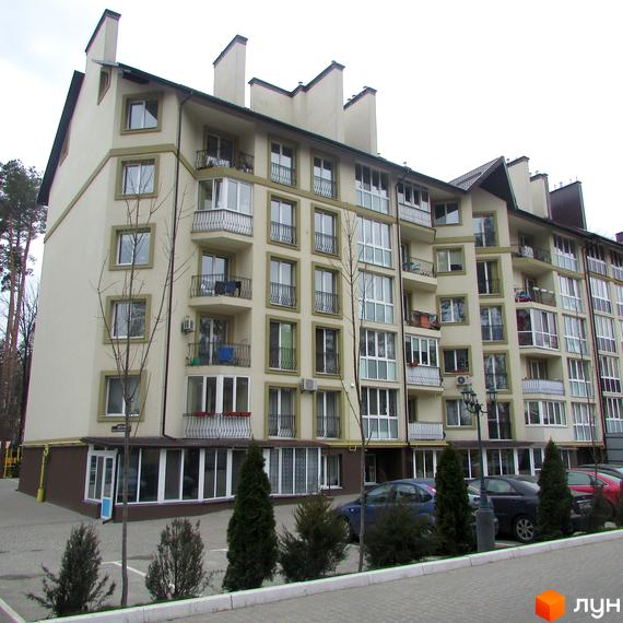 Зовнішній вигляд житлового комплексу Парковий з балконами та великими вікнами. На прибудинковій території розташовані дерева та автомобілі.