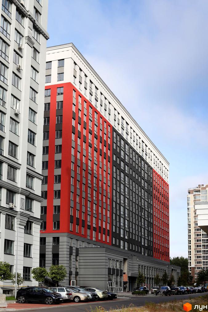 Зображення фасаду багатоповерхового будинку Житлового комплексу Irpin City. На передньому плані припарковані автомобілі.
