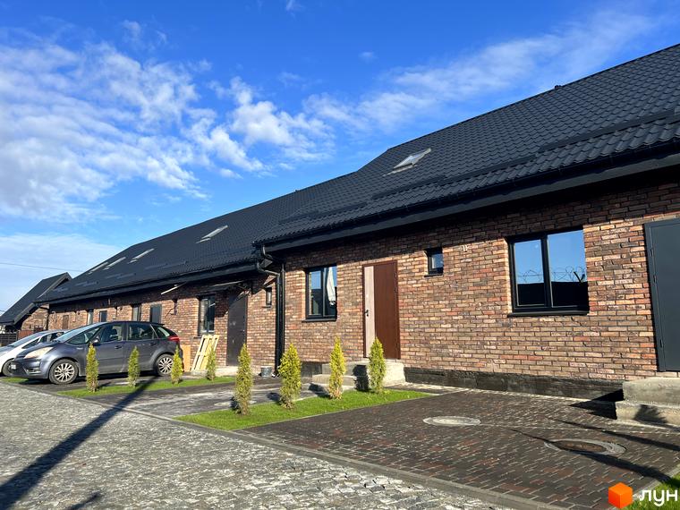 Цегляний будинок з чорним дахом в Містечку котеджів Бельгійське село, з паркуванням та газонами.