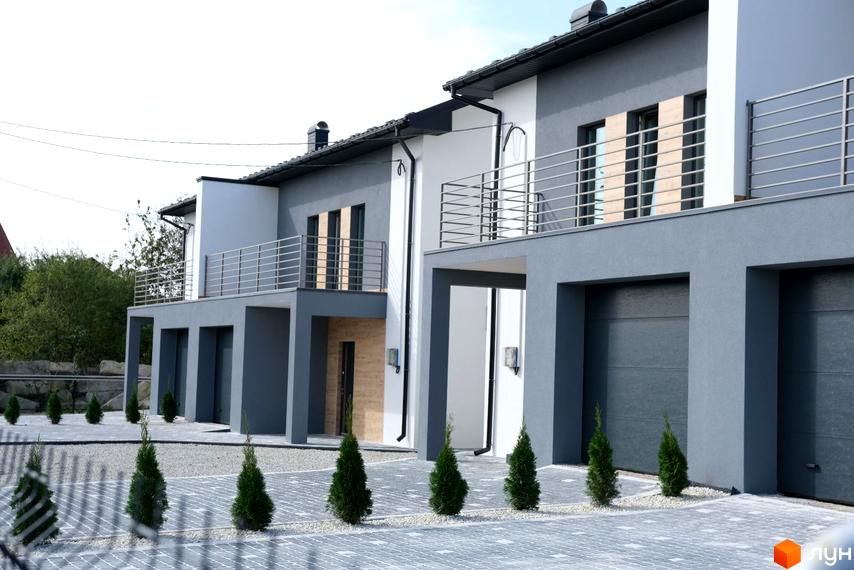 Зовнішній вигляд таунхаусів на вулиці Молодіжній. Двоповерхові будинки з сірим фасадом та балконами, перед будинками висаджені туї.