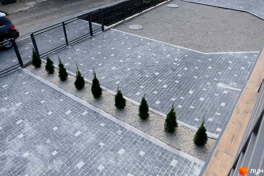 Вигляд на Житловий комплекс по вулиці Молодіжна з бруківкою та туями. На задньому плані парковка та газон.