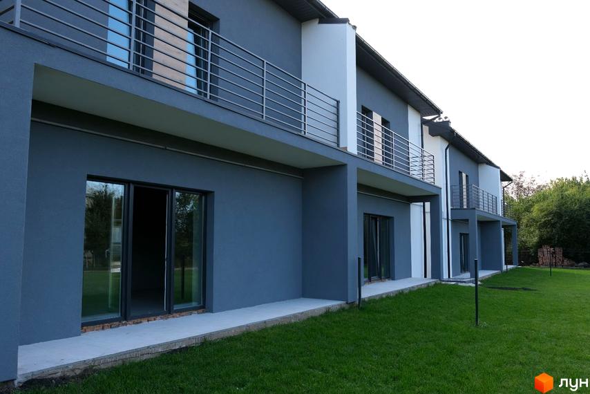 Зовнішній вигляд будинку на вулиці Молодіжній з балконами. Навколо будинку зелений газон.