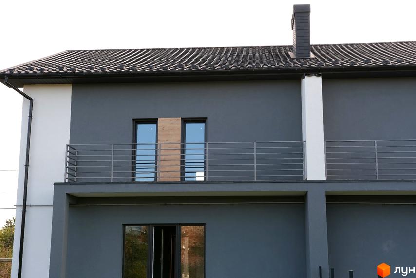 Фасад будинку на вул. Молодіжна з темно-сірою штукатуркою, білими елементами, балконом та темною черепицею на даху.