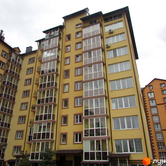 Висотна будівля ЖК Полтавський двір з великою кількістю вікон та балконів. Житловий комплекс має жовтий колір фасаду, поруч розташовані інші будівлі.