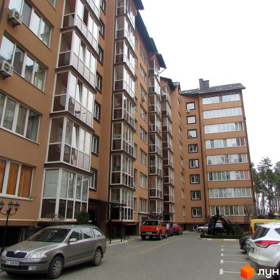 Зображення багатоповерхового будинку ЖК Полтавський двір з великими вікнами та балконами. На прибудинковій території є парковка для автомобілів.