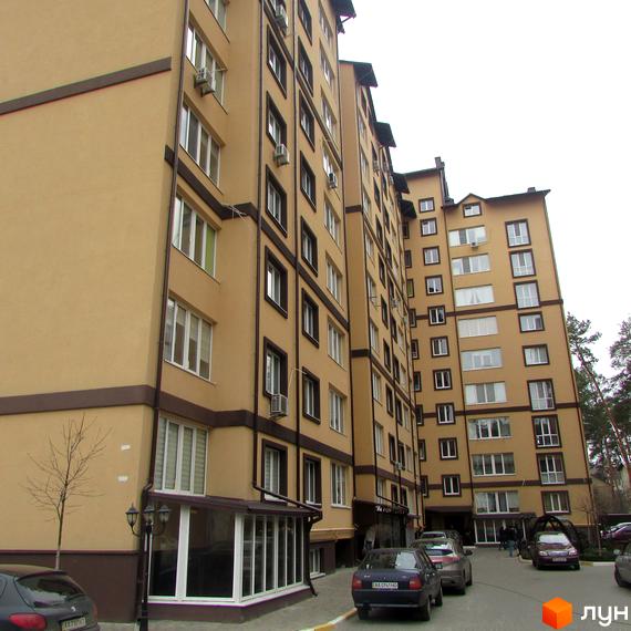 Високоповерховий будинок ЖК Полтавський двір з бежевим фасадом та коричневими акцентами. На території є парковка для автомобілів.